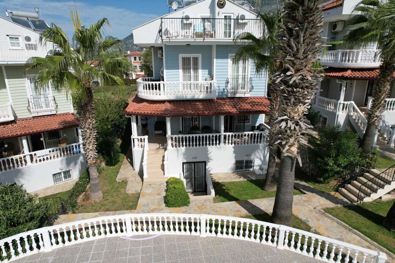 Mimosa F1 exterior — blue and white duplex with palm trees and gardens